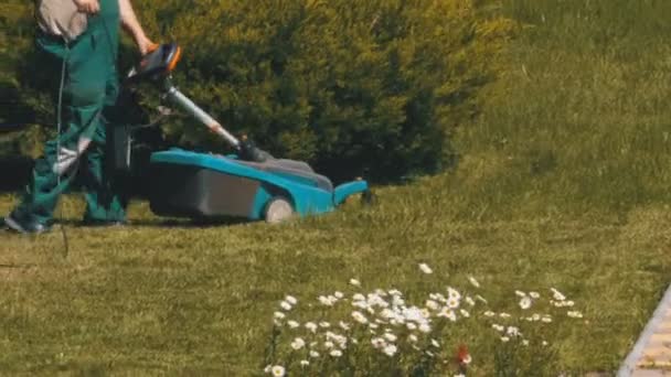 ポータブル電動芝刈り機を持つ男、公園の芝生に緑の草を刈っています。 — ストック動画