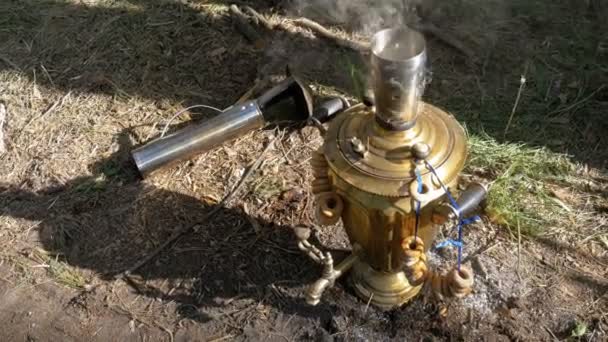 Big old Bronze samovar stands on the ground and prepares tea. — Stock Video