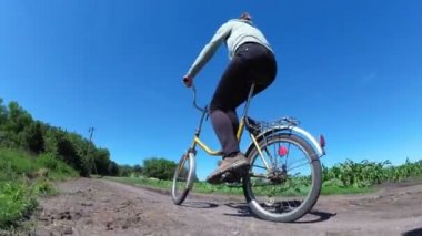 Genç kadın bir köyde kırsal bir yol boyunca Vintage bisiklet sürme