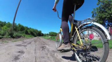 Genç kadın bir köyde kırsal bir yol boyunca Vintage bisiklet sürme. Ağır çekim.