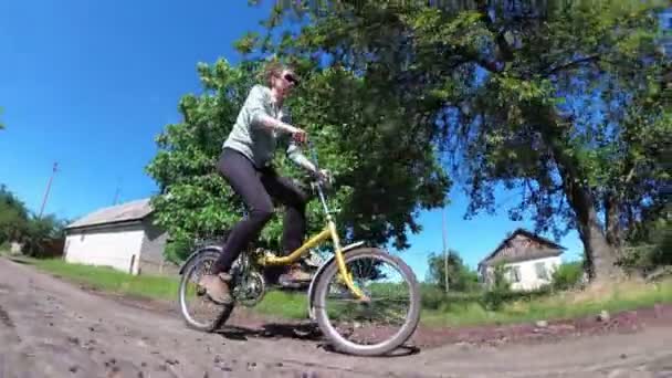 Jeune femme chevauchant vélo vintage le long d'une route rurale dans un village — Video