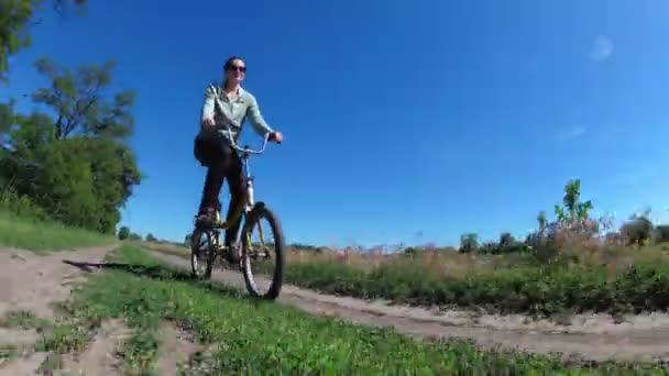 Mladá žena jízda historických kol po venkovské silnici ve vesnici — Stock video