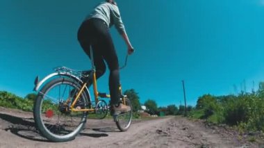 Genç kadın bir köyde kırsal bir yol boyunca Vintage bisiklet sürme