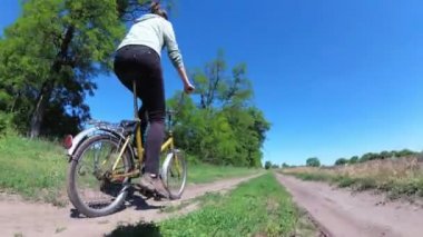 Genç kadın bir köyde kırsal bir yol boyunca Vintage bisiklet sürme