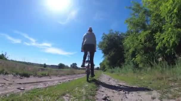 Joven mujer montando bicicleta vintage a lo largo de un camino rural en un pueblo — Vídeos de Stock