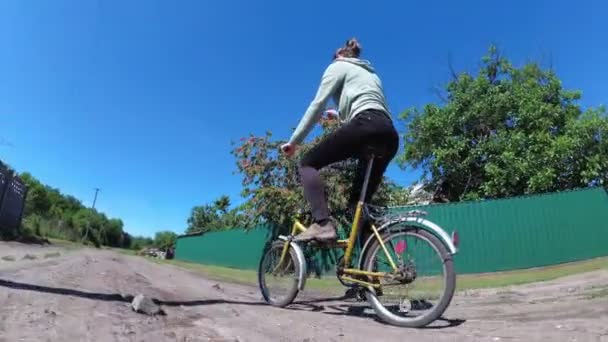 Ung kvinna Vintage cyklar längs en lantlig väg i en by — Stockvideo