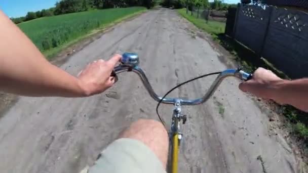 O homem está montando uma bicicleta em uma estrada rural na vila. Vista do peito na roda — Vídeo de Stock