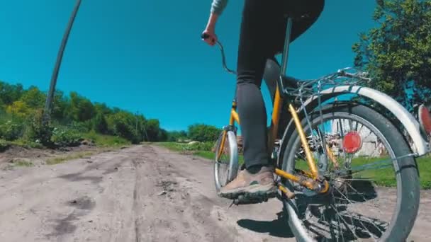 Joven mujer montando bicicleta vintage a lo largo de un camino rural en un pueblo. Moción lenta . — Vídeo de stock