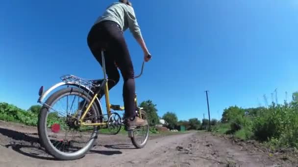 Молодая женщина на винтажном велосипеде по сельской дороге в деревне — стоковое видео
