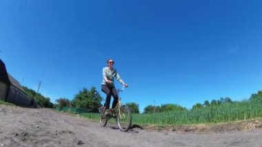 Genç kadın bir köyde kırsal bir yol boyunca Vintage bisiklet sürme