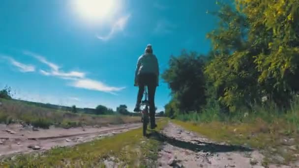 Mladá žena jízda historických kol po venkovské silnici ve vesnici — Stock video