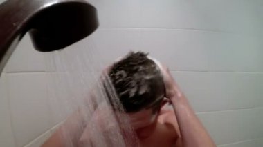 Adam kafasını duşta yıkar.