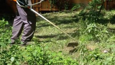 Adam Mows yavaş çekimde taşınabilir bir çim biçme makinesi kullanarak çimen