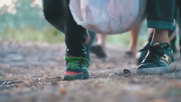 Piernas de una multitud de personas caminando a lo largo del camino en el bosque por la noche — Vídeo de stock