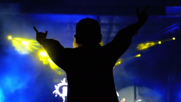 Σιλουέτα ενός κοριτσιού σε μια ροκ συναυλία με τα χέρια απλωμένα. Φεστιβάλ μουσικής σκηνής και φώτα — Αρχείο Βίντεο