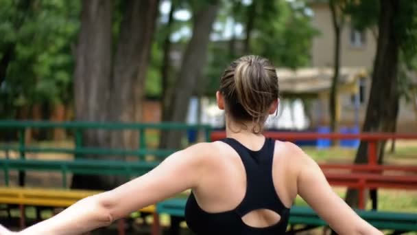 Tânăra sportivă atletică efectuează o încălzire a mâinilor pe terenul sportiv din parc — Videoclip de stoc