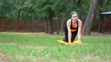 Yeşil çim üzerinde bir parkta bir halı üzerinde yalan Fitness spor kıyafeti kadında genç atlet nişanlı