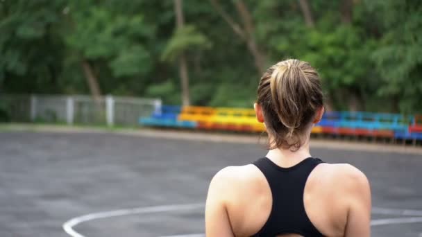 Bakifrån på ung idrottsman kvinna i Sport Outfit promenader längs den sport Feld i parken — Stockvideo