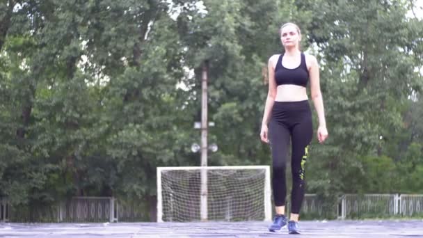 Mujer atleta joven en traje deportivo comprometida en la aptitud en el campo de deportes en el parque . — Vídeos de Stock