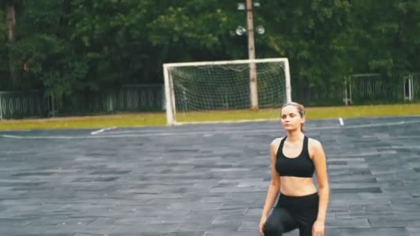 运动服装的年轻运动员妇女在公园的运动场上从事健身运动. — 图库视频影像