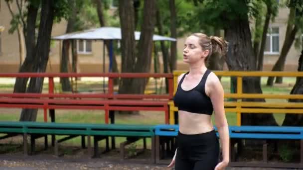 Jovem atleta mulher em roupa esportiva envolvida em fitness no campo de esportes no parque . — Vídeo de Stock