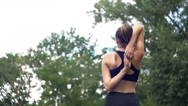 Jeune athlète femme en tenue de sport engagée dans la remise en forme sur le terrain de sport dans le parc . — Video