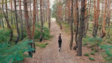 Çam Tee orman yolu işleten genç kadına arkadan havadan görünümü