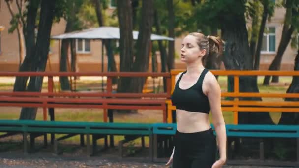 Tânăra sportivă în costum sportiv angajată în fitness pe terenul sportiv din parc . — Videoclip de stoc