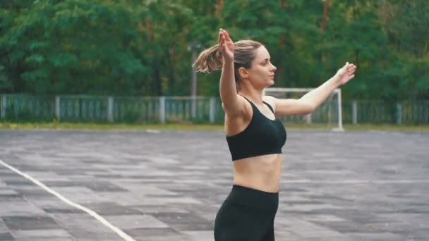 Jovem atleta mulher em roupa esportiva envolvida em fitness no campo de esportes no parque . — Vídeo de Stock