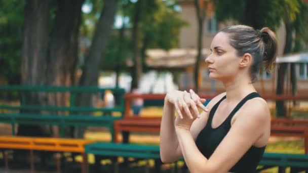 Unga atletisk sport flicka utför en uppvärmning av händer på idrottsplanen i parken — Stockvideo