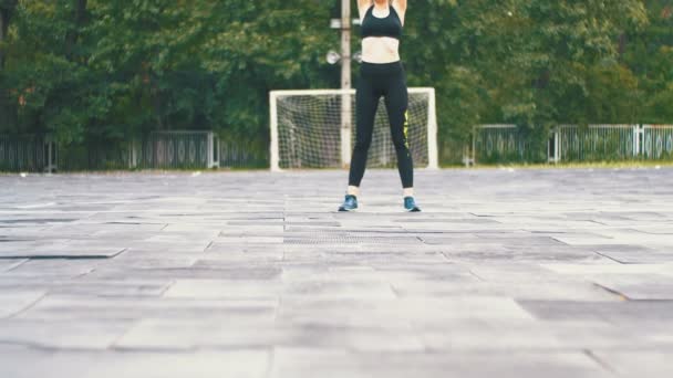 Mujer atleta joven en traje deportivo comprometida en la aptitud en el campo de deportes en el parque . — Vídeo de stock