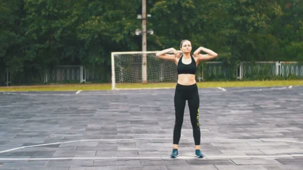 Mujer atleta joven en traje deportivo comprometida en la aptitud en el campo de deportes en el parque . — Vídeos de Stock