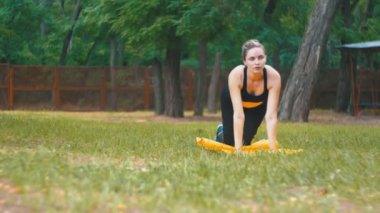 Pratik Yoga bir halı yeşil çim üzerinde bir parkta yatan genç sporcu kadın spor kıyafeti nişanlı