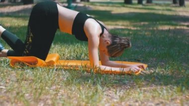 Pratik Yoga bir halı yeşil çim üzerinde bir parkta yatan genç sporcu kadın spor kıyafeti nişanlı