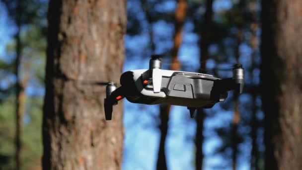 Drone with a camera hovers in the air. Quadcopter flies above the ground in the forest — Stock Video