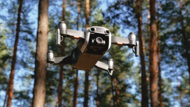 Drone con una cámara se cierne en el aire. Quadcopter vuela sobre el suelo en el bosque — Vídeos de Stock