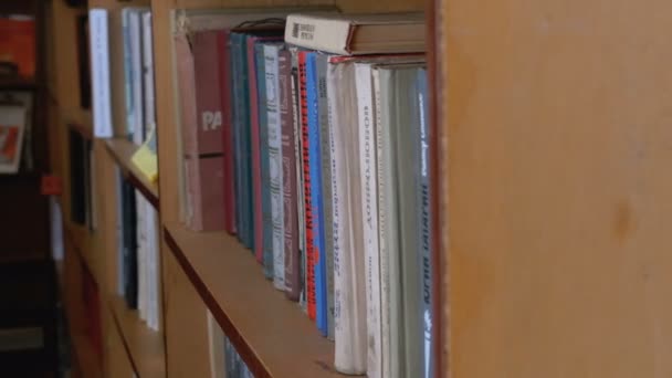 Τα βιβλία στα ράφια της βιβλιοθήκης. Σωρούς από βιβλία στα ράφια της βιβλιοθήκης του παλιού — Αρχείο Βίντεο