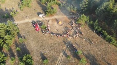 Bir çam ormanı içinde büyük bir kamp ateşi yakın kişi organize toplama havadan görünümü