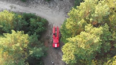 Üstten görünüm için bir çam ormanı içinde kırmızı itfaiye arabası. Orman yolu üzerinde uçan havadan görünümü