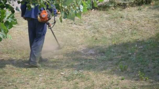 El hombre corta hierba usando una cortadora de césped portátil — Vídeos de Stock