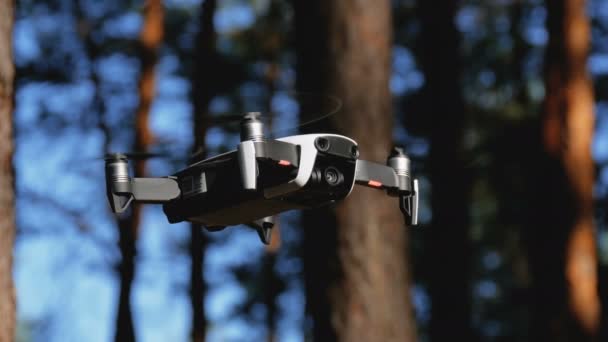 Drone med kamera svevende i luften. Quadcopter flyr over bakken i skogen – stockvideo