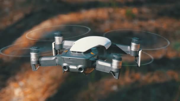 Drone con una cámara se cierne en el aire. Quadcopter vuela sobre el suelo en el bosque — Vídeos de Stock