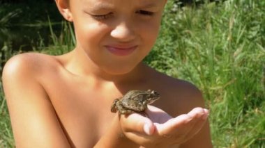 Küçük çocuk tutan elleri ve konturlar parmak Nehri yakınında sahilde tarafından onun Kurbağa kurbağa