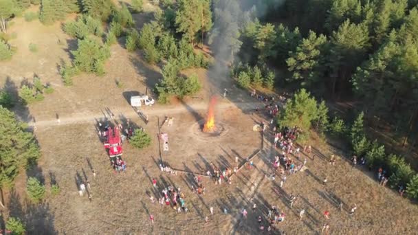 Luchtfoto van het georganiseerde bijeenkomst van personen in de buurt van een groot kampvuur in een dennenbos — Stockvideo