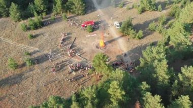 Bir çam ormanı içinde büyük bir kamp ateşi yakın kişi organize toplama havadan görünümü