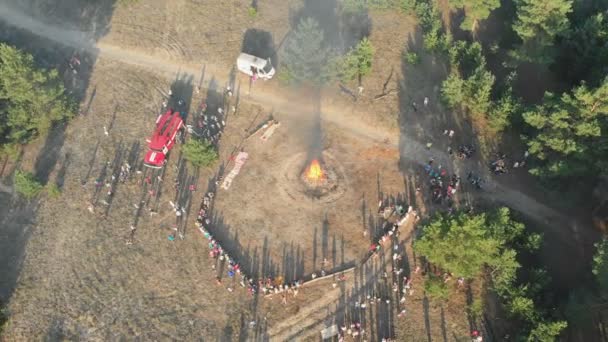 Vista aérea do Encontro Organizado de Pessoas perto de uma Grande Fogueira em uma Floresta de Pinheiro — Vídeo de Stock