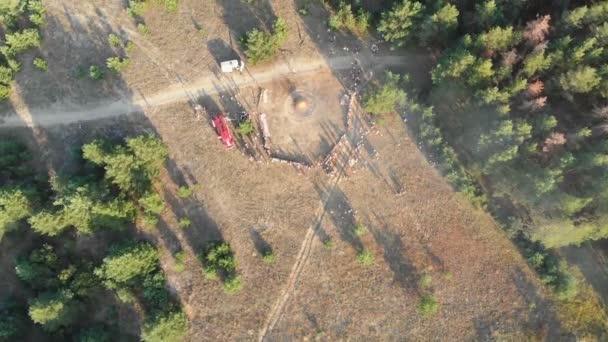 Εναέρια άποψη του οργανωμένη συγκέντρωση των ατόμων κοντά σε ένα μεγάλο Campfire σε ένα πευκόφυτο δάσος — Αρχείο Βίντεο