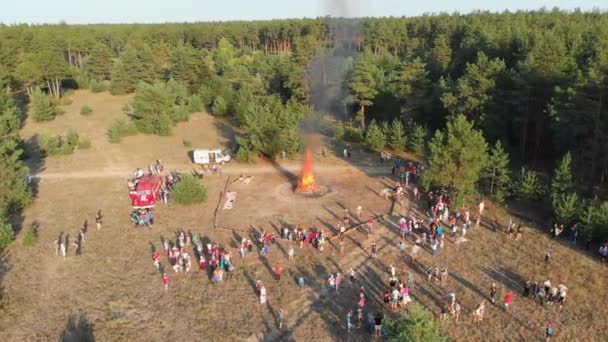 Luchtfoto van het georganiseerde bijeenkomst van personen in de buurt van een groot kampvuur in een dennenbos — Stockvideo