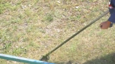 Taşınabilir bir çim biçme makinesi kullanarak çim adam mows