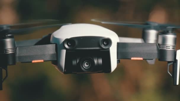 Drone with a camera hovers in the air. Quadcopter flies above the ground in the forest — Stock Video